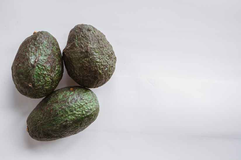 ripe avocados with uneven peel on white background